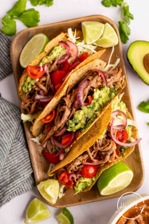 Brisket Tacos on a cutting board with lime wedges.