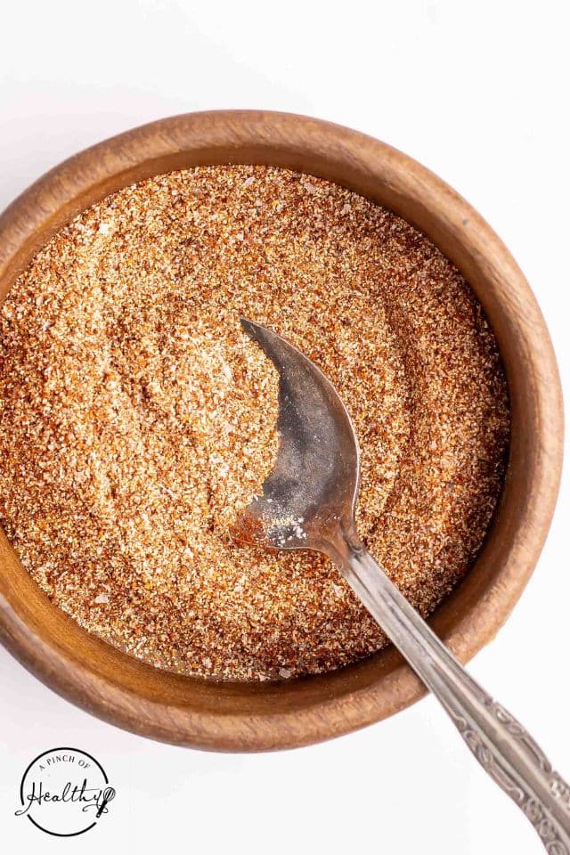 Seasoning blend for brisket tacos in a wooden bowl with a spoon inside.