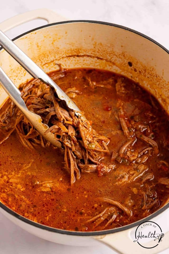 Cooked shredded brisket in the braising liquid after cooking.