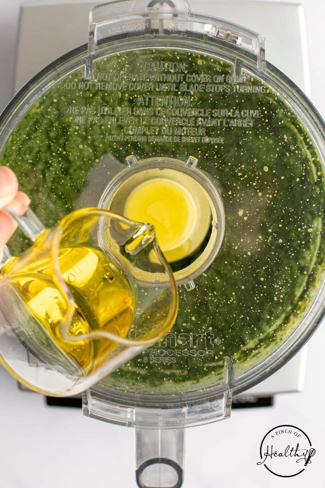 Oil being drizzled into the food processor while it is running.