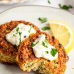 Salmon cakes on a white plate with a slice of lemon.