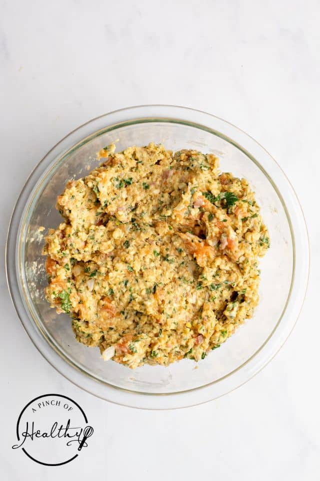 Salmon cake mixture in a glass bowl before being formed into patties.
