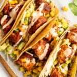 Salmon Tacos on a platter with sauce on top.