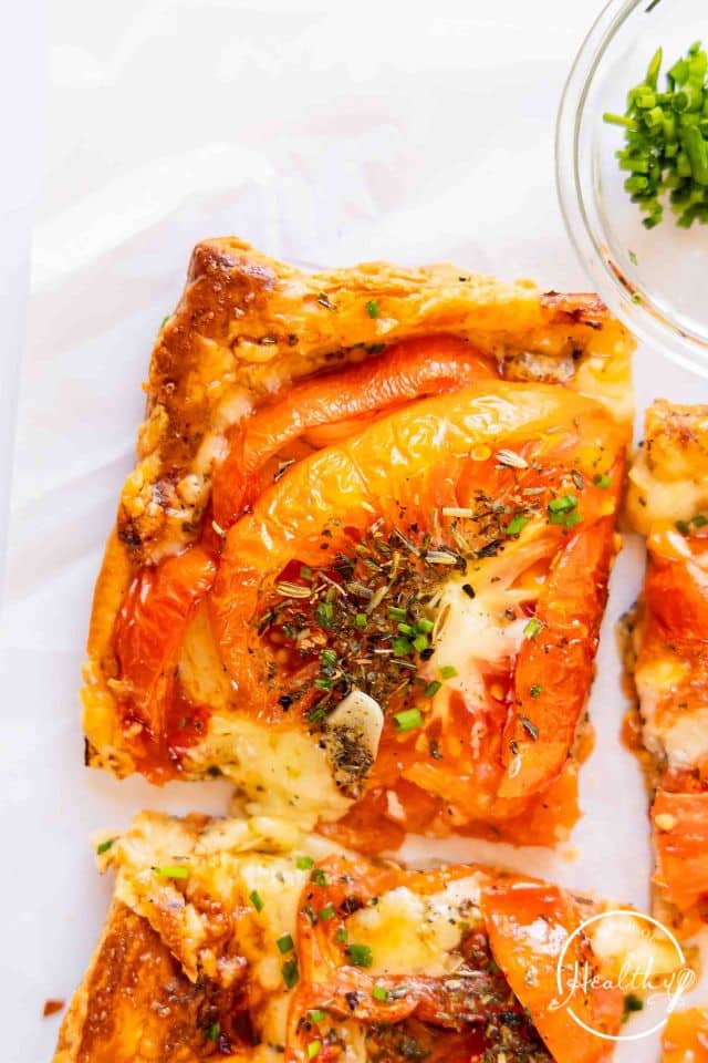 A slice of tomato tart on a white background.