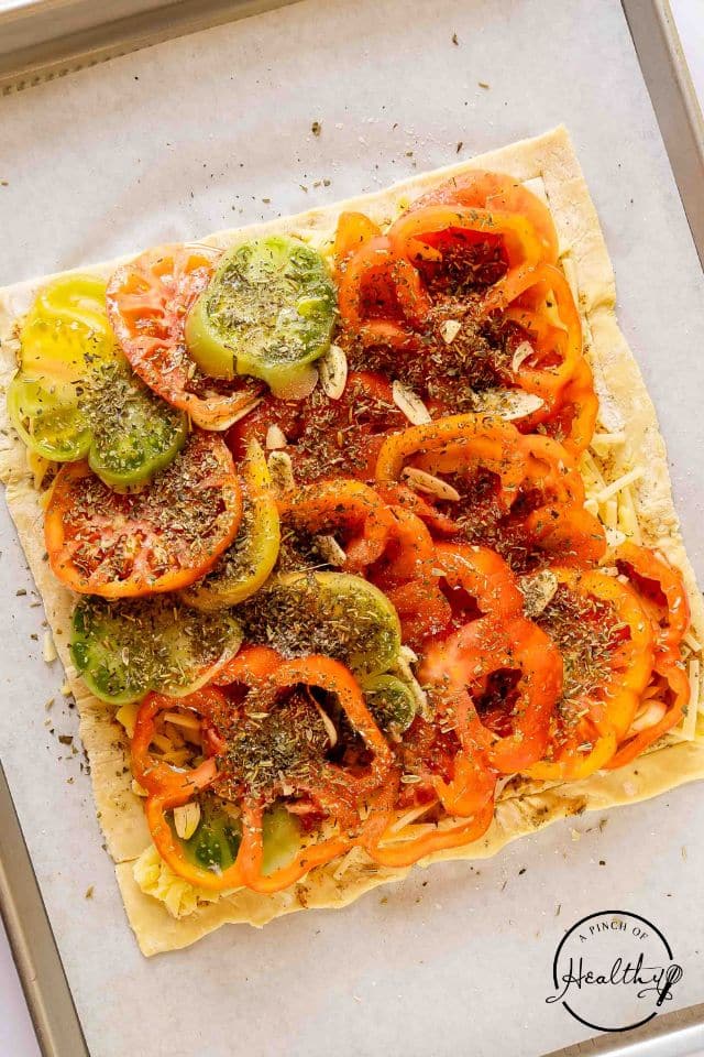Seasoned tomato tart on a prepared baking sheet.