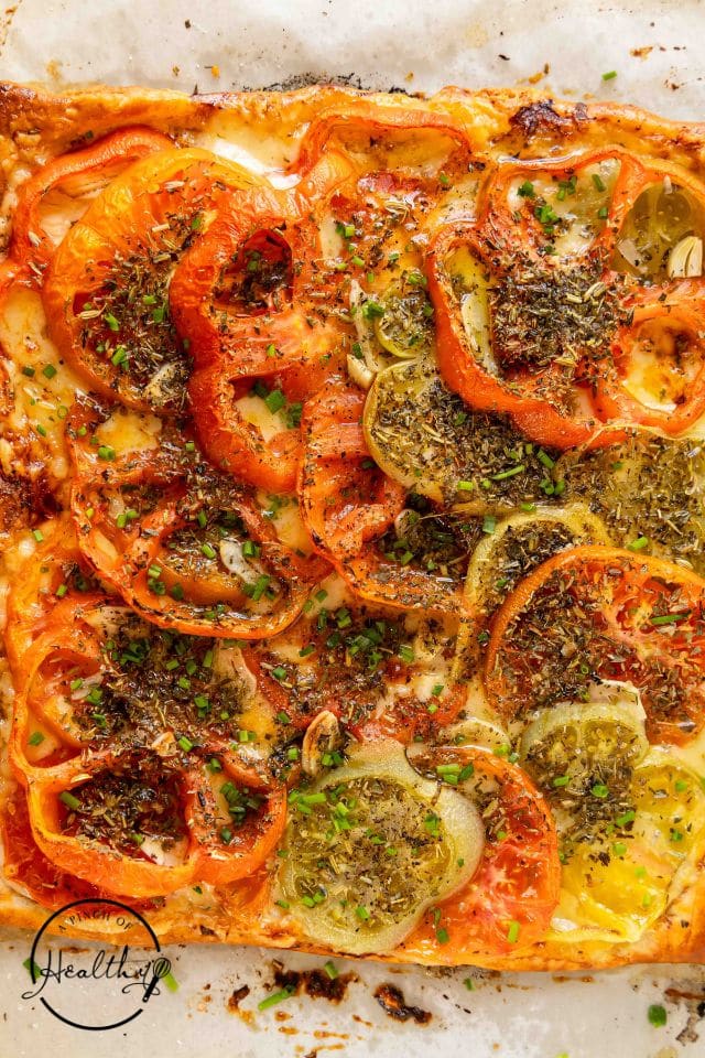 Baked tomato tart made with heirloom tomatoes on a white background.