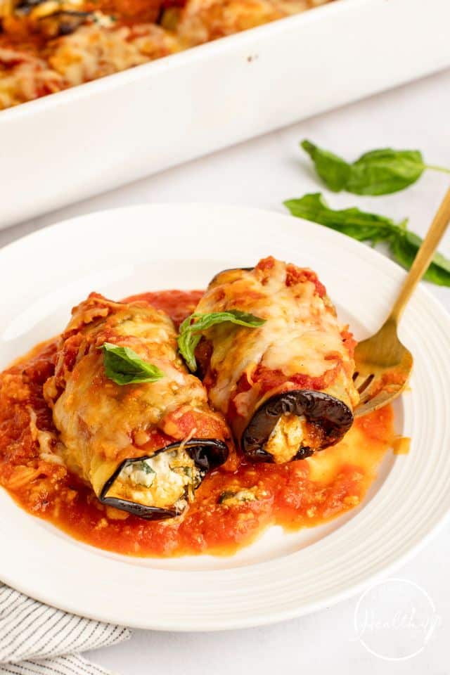 Eggplant Rollatini on a white plate with a gold fork. 