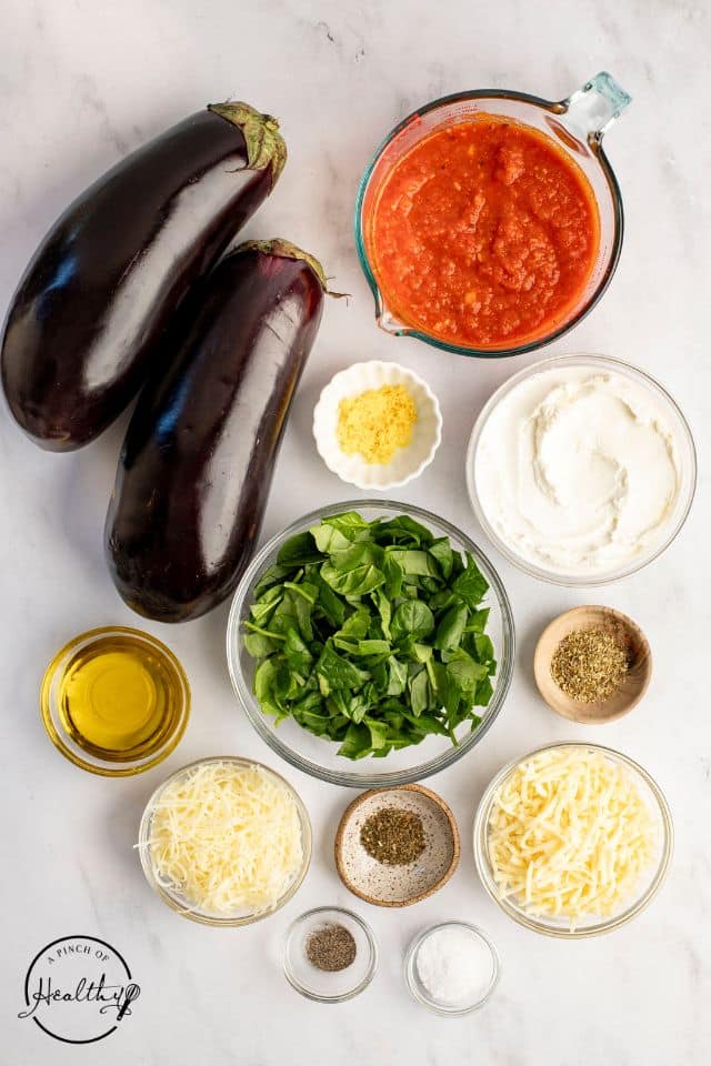 Ingredients for eggplant rollatini on a white background in separate containers.