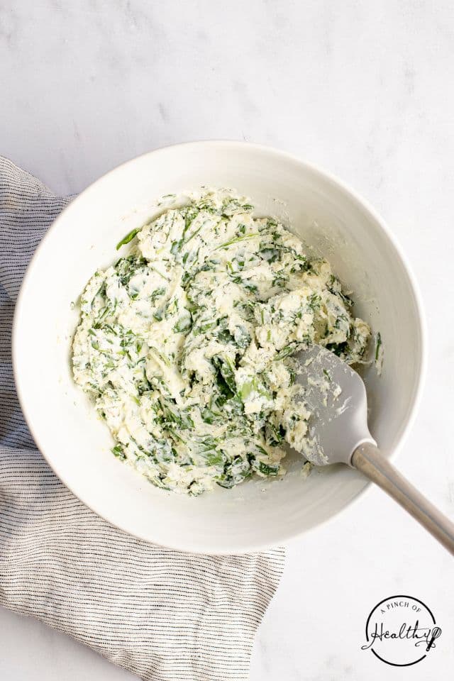 Spinach mixture for eggplant rollatini mixed together in a white bowl.