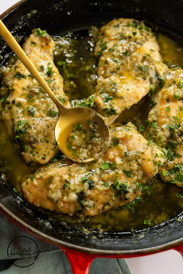 Garlic butter chicken with a gold spoon pouring garlic butter sauce over the chicken.