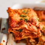 Homemade Lasagna slice being held up by a spatula.