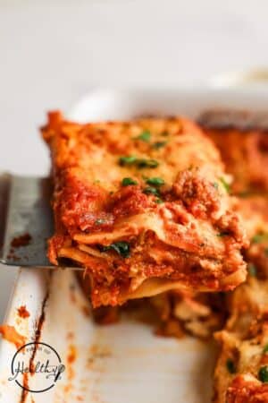Homemade Lasagna slice being held up by a spatula.