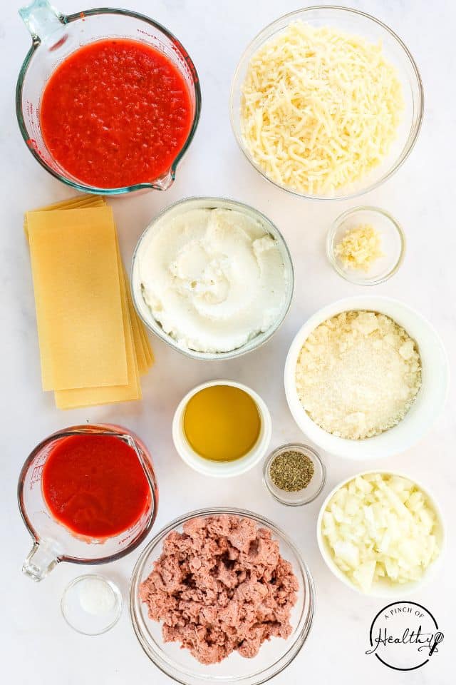 Ingredients for homemade lasagna on a white background in separate containers.