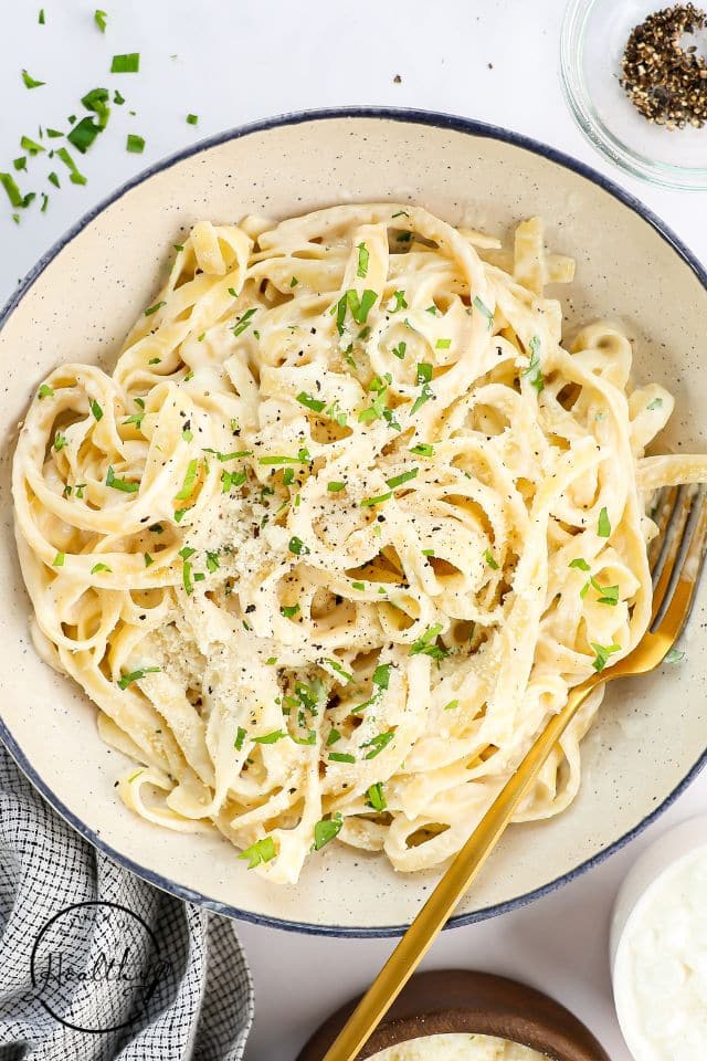 Healthier alfredo sauce with cottage cheese and milk tossed with pasta in a large serving bowl.