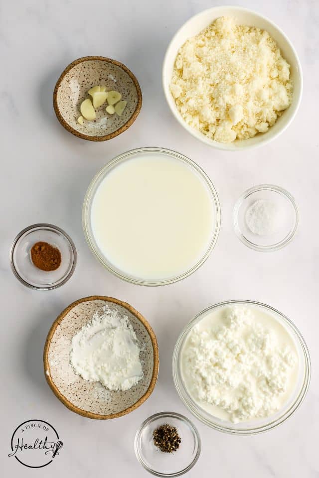 Ingredients for alfredo sauce in separate containers on a white background.