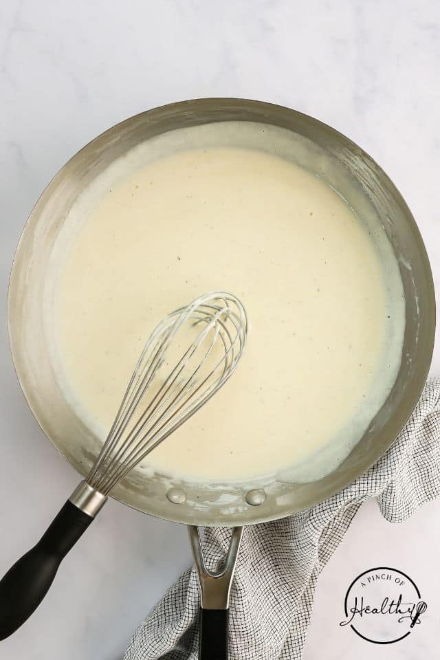 Healthy alfredo in a skillet after being cooked and whisked.