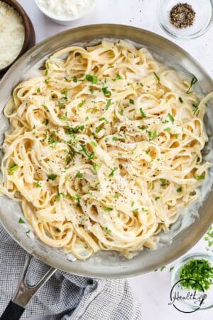 Alfredo sauce in a skillet tossed with fettuccine.