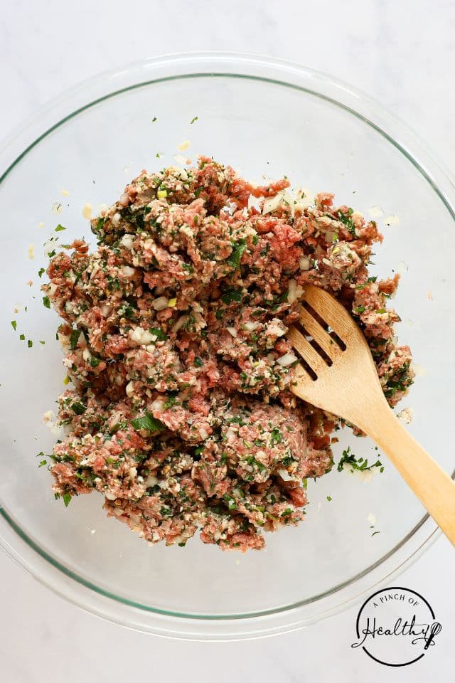 Meatball ingredients in a large glass bowl after being mixed together.