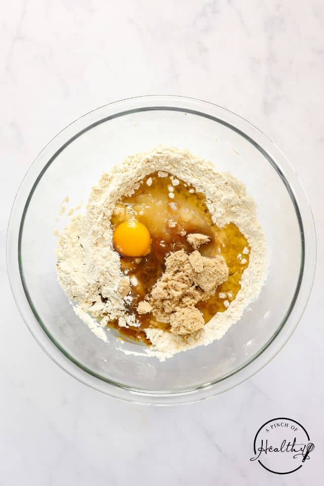 Eggs and vanilla added to the dry ingredients for applesauce muffins.