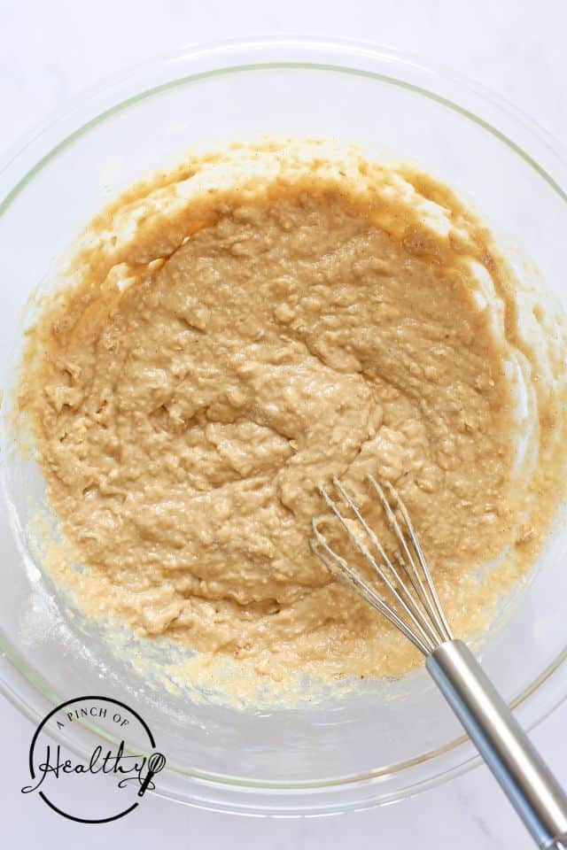 Batter for applesauce muffins after being mixed in a large glass bowl with a whisk.
