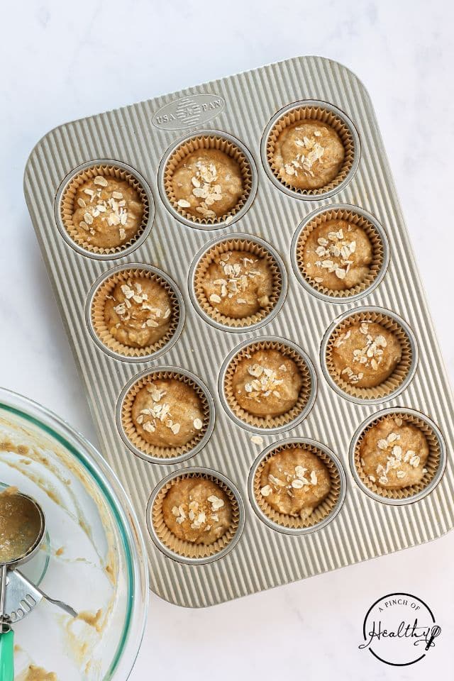 Applesauce muffin batter in a prepared muffin tin before being baked.