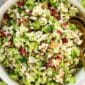 Broccoli Cauliflower Salad in a large white bowl with a gold spoon.