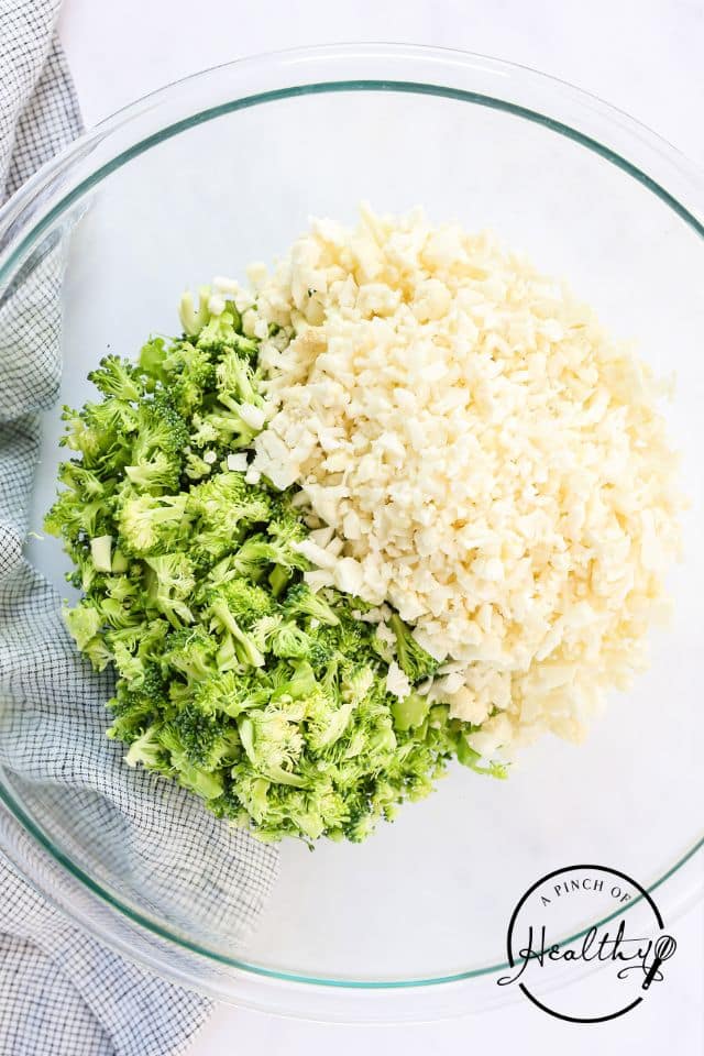 Broccoli and cauliflower in a glass bowl before being mixed together.