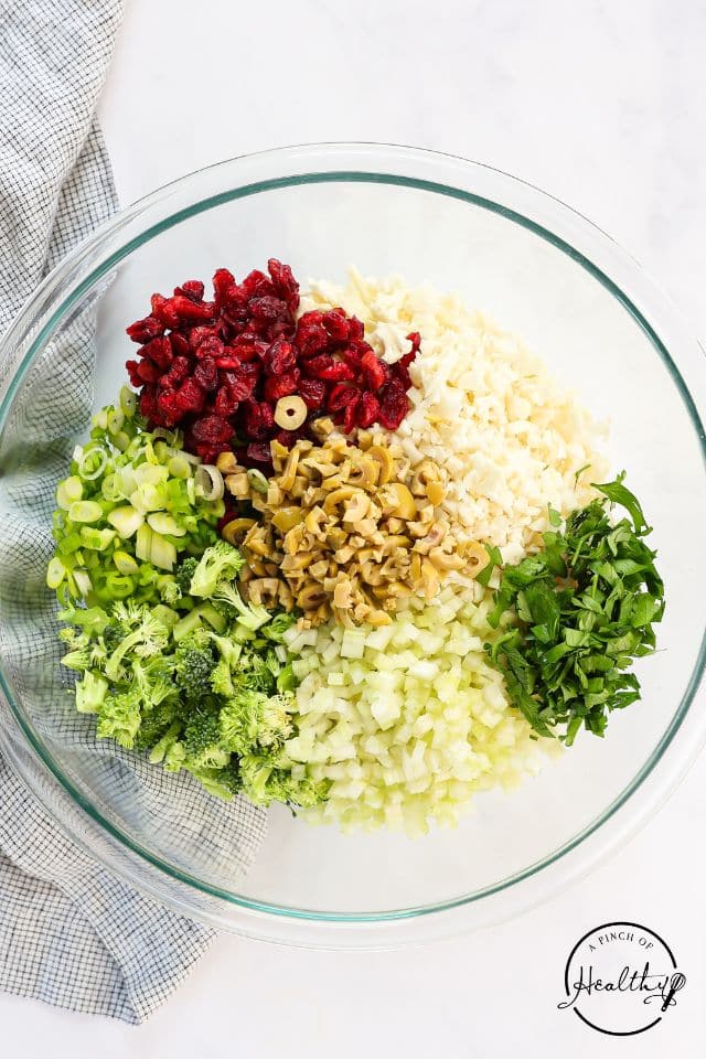 The rest of the mix-ins for the broccoli cauliflower salad in a glass bowl.