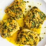 Crock pot chicken thighs on a white plate with sauce poured over the top.
