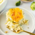 Broccoli Rice Casserole on a white plate with a gold fork.