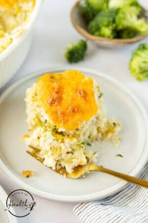 Broccoli Rice Casserole on a white plate with a gold fork.