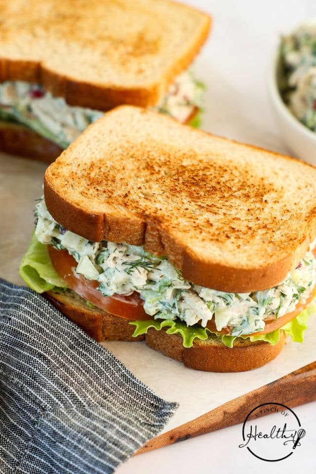 A full chicken salad sandwich on a parchment-lined cutting board.