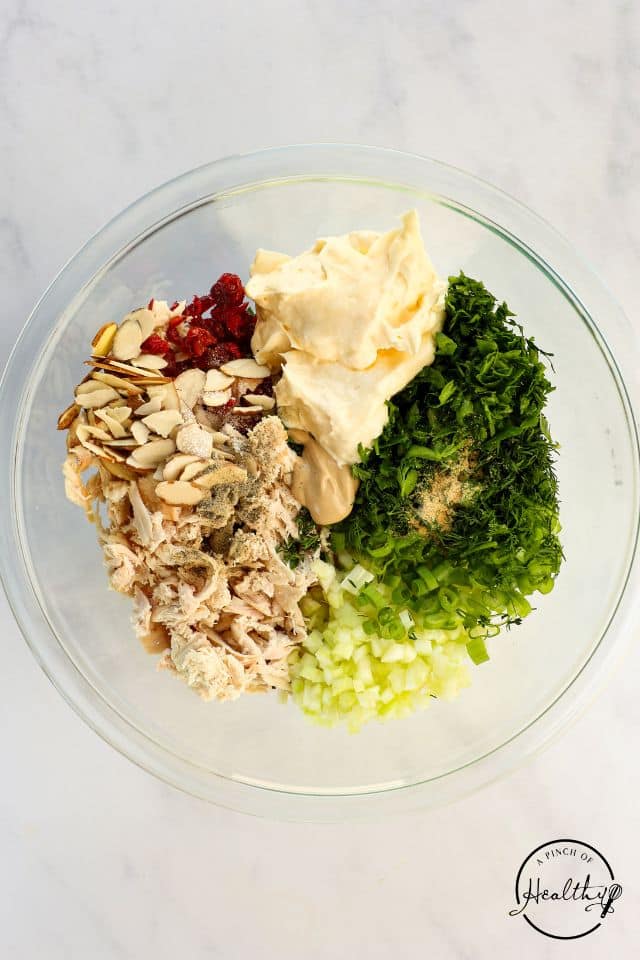 Ingredients for chicken salad sandwiches in a glass bowl before being mixed together.