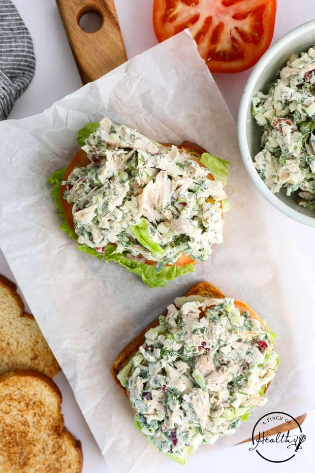 Chicken salad sandwiches after being assembled without a top piece of bread on, showing all of the different elements.