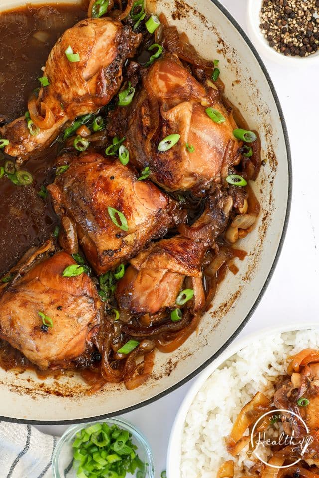 Cooked Chicken adobo in a large skillet with green onion on top.