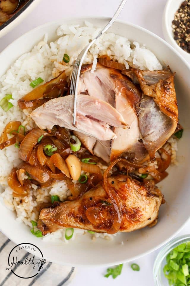 Chicken adobo in a large white serving bowl with rice.
