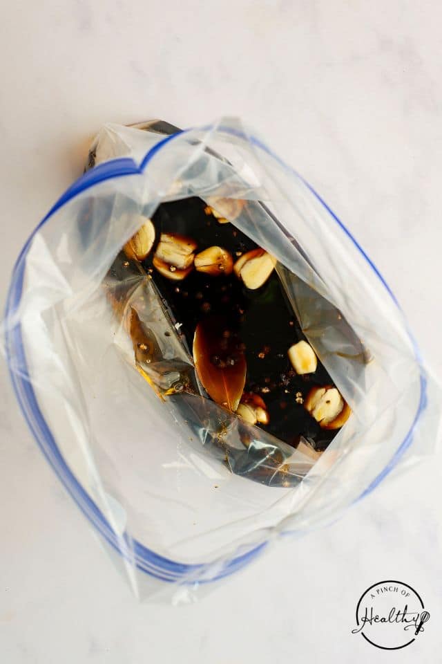 Marinade ingredients for chicken adobo in a large plastic bag.