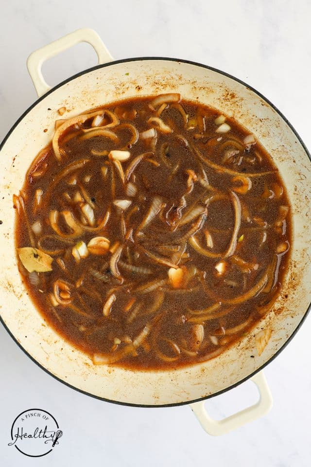 Sauce for chicken adobo being cooked in a large skillet.