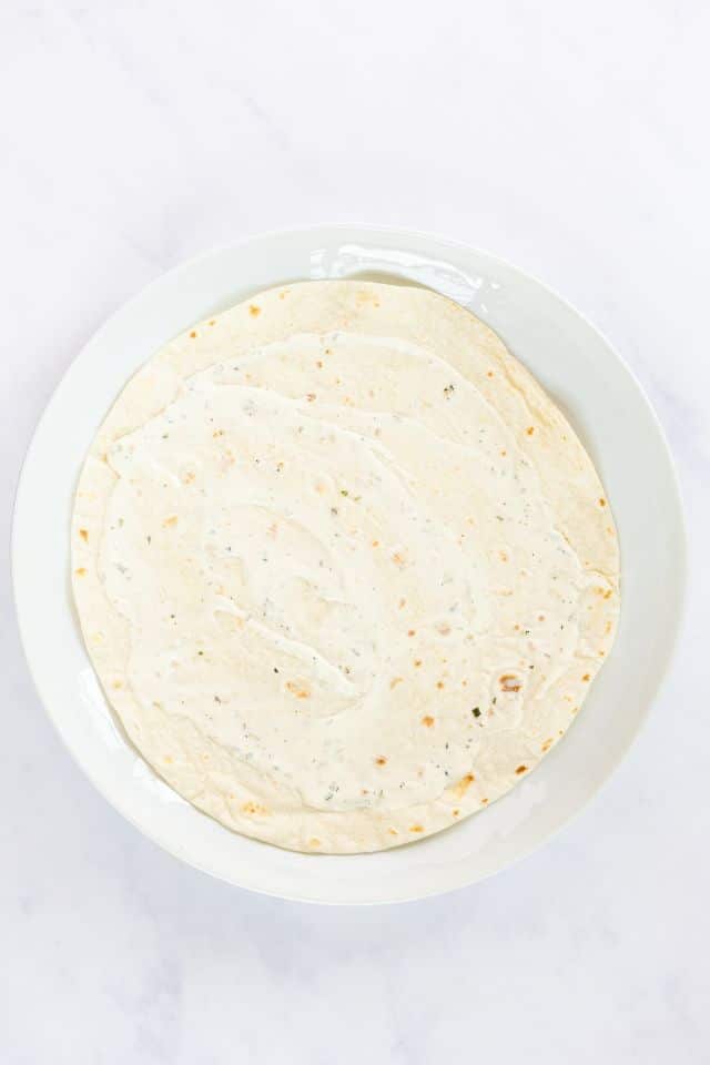 Tortilla with ranch spread onto it.