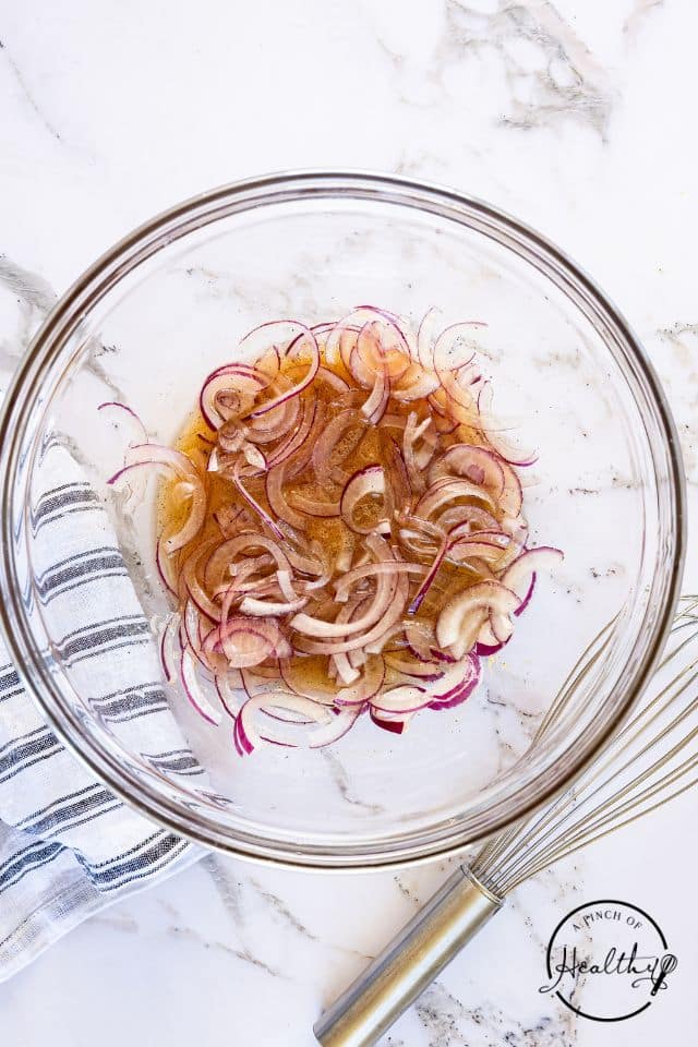 Dressing for German potato salad in a large glass bowl.