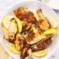 A cut up roasted rotisserie chicken on a white serving platter with lemon slices