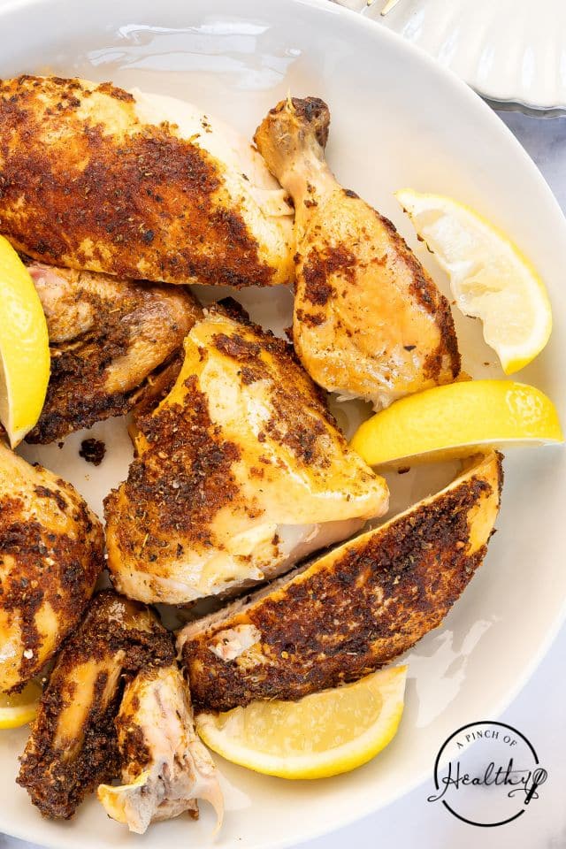 A cut up oven-roasted rotisserie chicken on a white platter.