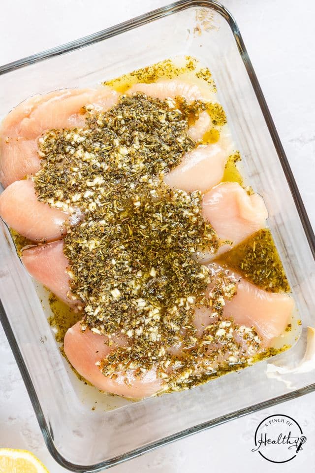 Chicken with marinade poured over the top in a large glass container.
