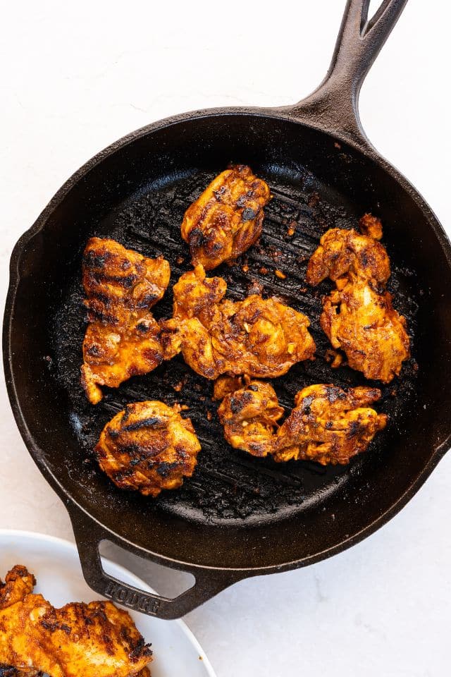 Marinated chicken for street tacos being cooked in a cast-iron grill pan.