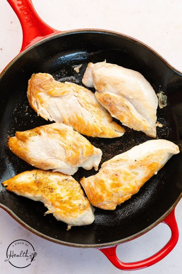 Chicken being browned in a skillet for shredded chicken tacos.