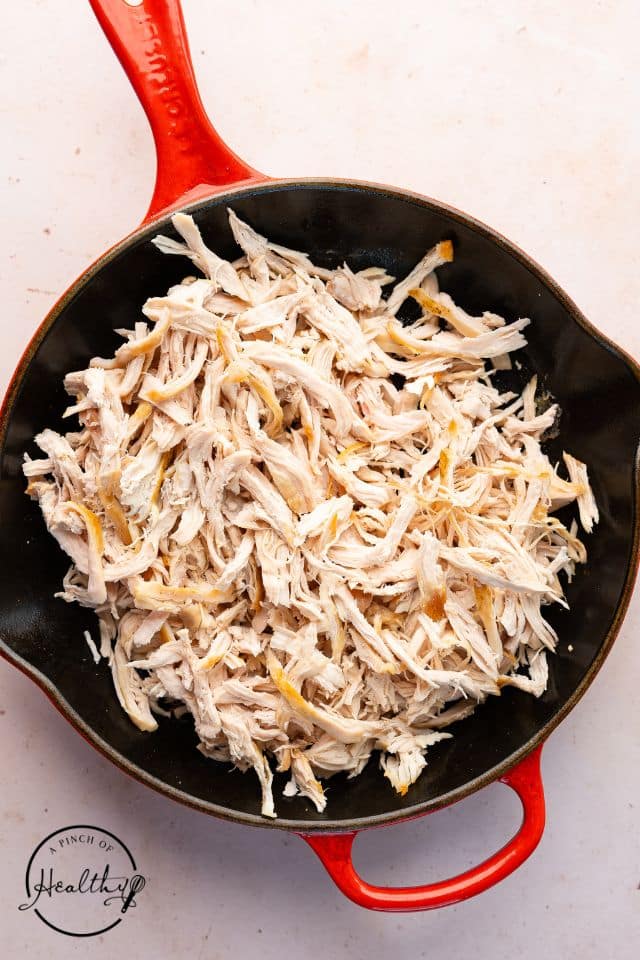 Shredded chicken in a skillet before being seasoned.