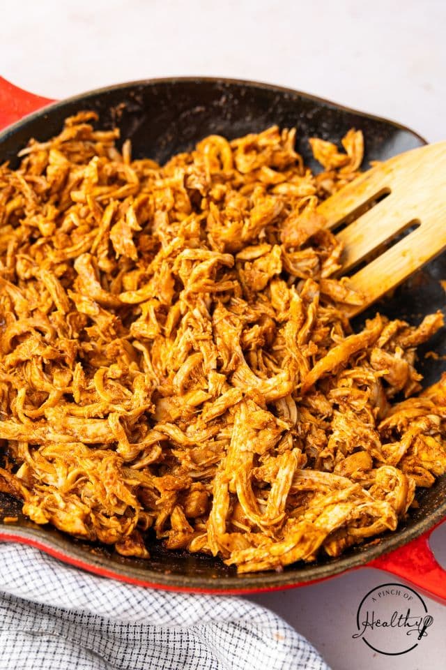 Shredded chicken tacos in a skillet before being built.