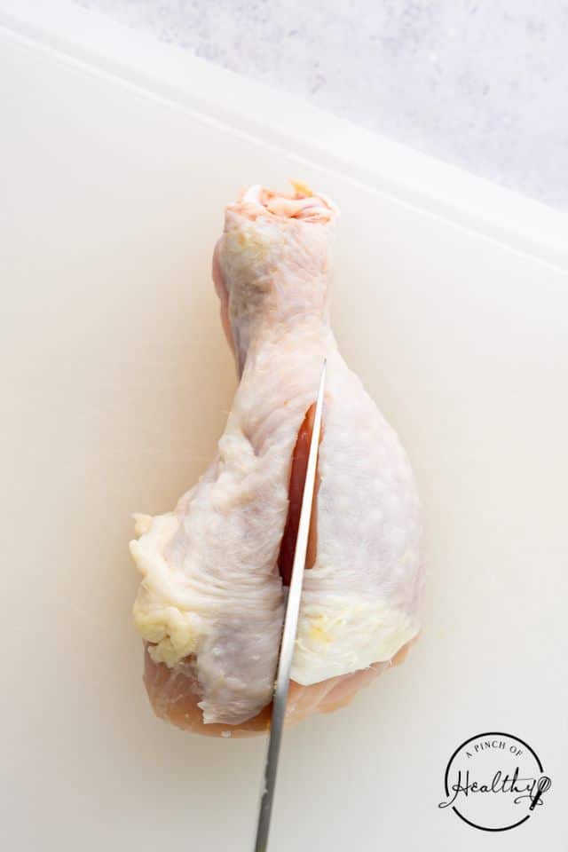 The process of butterflying a chicken leg.