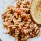 Hamburger casserole on a white textured plate with a slice of garlic bread